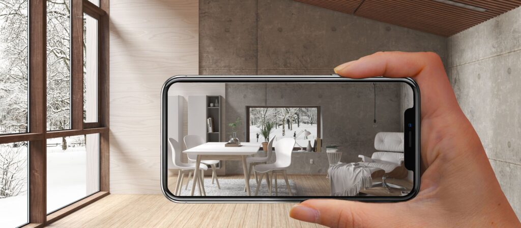iPhone Screen pointing at empty room. In the screen a living room furniture is shown to visualize what it coudl look like.